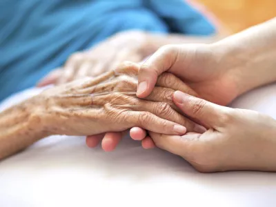 Woman holding senior woman's hand on bed / Foto: Pharrel Wiliams