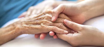 Woman holding senior woman's hand on bed / Foto: Pharrel Wiliams
