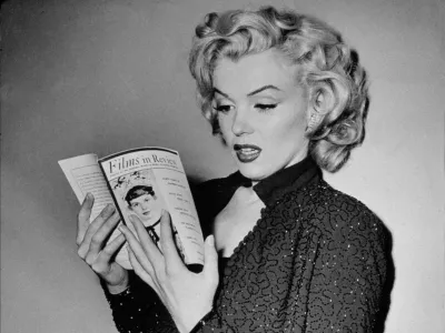 2AX4XFR 1952 november, Hollywood: MARILYN MONROE read a movie magazine with a review of one of his movie during the making-of GENTLEMEN PREFER BLONDES (Gli uomini preferiscono le bionde - 1952) by Jean Negulesco - 20th Century Fox productions - FILM - Actress - attrice - MOVIE - CINEMA - sex symbol - sexy pose - blonde hair - bionda - capelli biondi - gioiello - gioielli - bigiotteria - bijoux - jewel - jewels - jewellery - glitter dress - strass - diva - star - superstar - HOLLYWOOD - anni '50 - 50's - lettura - personalta celebrita che legge - personality celebrity celebrities personalitie. Image shot 1952. Exact date unknown.