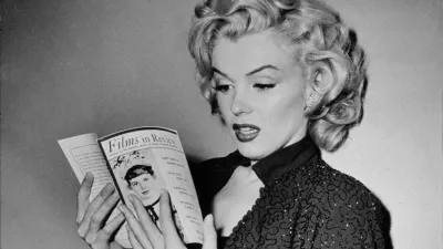 2AX4XFR 1952 november, Hollywood: MARILYN MONROE read a movie magazine with a review of one of his movie during the making-of GENTLEMEN PREFER BLONDES (Gli uomini preferiscono le bionde - 1952) by Jean Negulesco - 20th Century Fox productions - FILM - Actress - attrice - MOVIE - CINEMA - sex symbol - sexy pose - blonde hair - bionda - capelli biondi - gioiello - gioielli - bigiotteria - bijoux - jewel - jewels - jewellery - glitter dress - strass - diva - star - superstar - HOLLYWOOD - anni '50 - 50's - lettura - personalta celebrita che legge - personality celebrity celebrities personalitie. Image shot 1952. Exact date unknown.