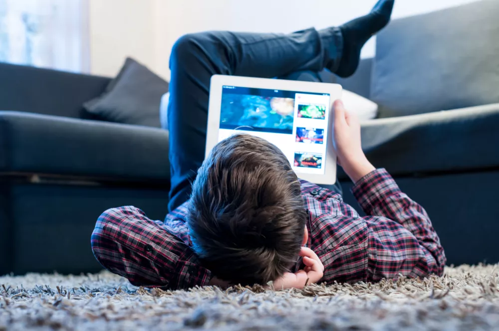 teenager with tablet while lying on the floor in the room
