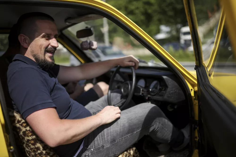 Tarik Fatic sits down in the Reliant Regal, an exact copy of the famous BBC TV show &nbsp;"Only Fools and Horses" iconic yellow car in Hadzici, suburb of Sarajevo, Bosnia, Wednesday, June 4, 2025. (AP Photo/Armin Durgut)