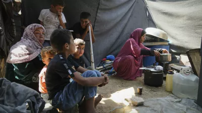 Tahreer Abu Jazar, 36, right, prepares an Eid al-Adha meal for her family inside their tent at a camp for displaced Palestinians in Mawasi Khan Younis, Gaza Strip, on Friday, June 6, 2025. (AP Photo/Abdel Kareem Hana)