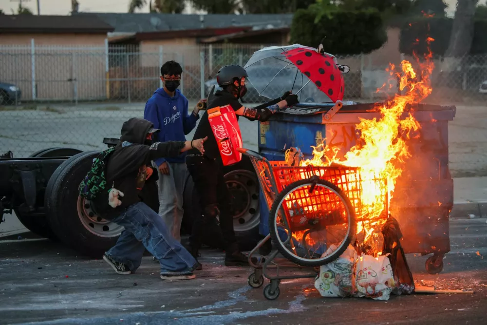 Protesters stand next to a burning shopping cart during a standoff between police and protesters following multiple detentions by Immigration and Customs Enforcement (ICE), in the Los Angeles County city of Paramount, California, U.S., June 7, 2025.  REUTERS/Daniel Cole / Foto: Daniel Cole