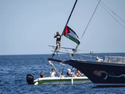 Climate activist Greta Thunberg stands near a Palestinian flag after boarding the Madleen boat and before setting sail for Gaza along with activists of the Freedom Flotilla Coalition, departing from the Sicilian port of Catania, Italy, Sunday, June 1, 2025. (AP Photo/Salvatore Cavalli)