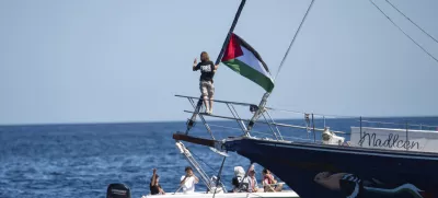 Climate activist Greta Thunberg stands near a Palestinian flag after boarding the Madleen boat and before setting sail for Gaza along with activists of the Freedom Flotilla Coalition, departing from the Sicilian port of Catania, Italy, Sunday, June 1, 2025. (AP Photo/Salvatore Cavalli)