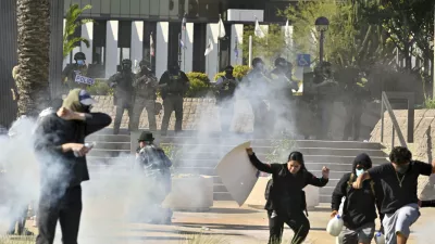 Protesters run from police as they use tear gas and flash-bangs at the Federal Building in Santa Ana, Calif., on Monday, June 9, 2025. (Jeff Gritchen/The Orange County Register via AP)