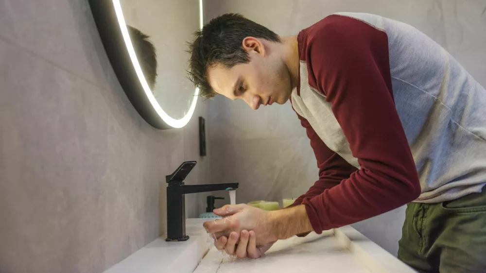 Young man carefully washes his hands in a modern bathroom, promoting hygiene, health, and responsible daily habits in a clean and organized environment. High quality photo / Foto: Stockseller_ukr