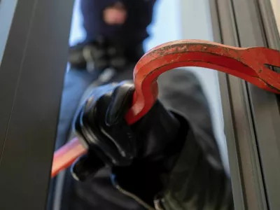 Burglary with crowbar. Burglar in balaclava breaking a glass door. Masked housebreaker entering a house for stealing in the daytime. / Foto: Rawf8