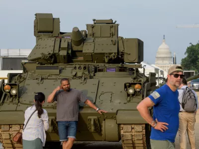 People pass by and take photos with a tank, parked on the National Mall, during preparations for an upcoming military parade commemorating the Army's 250th anniversary and coinciding with President Donald Trump's 79th birthday, Thursday, June 12, 2025, in Washington. (AP Photo/Rod Lamkey, Jr.)
