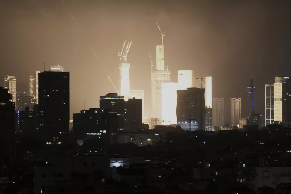 An explosion caused by a projectile strike illuminates the skyline in Tel Aviv, Israel, early Saturday, June 14, 2025. (AP Photo/Leo Correa)