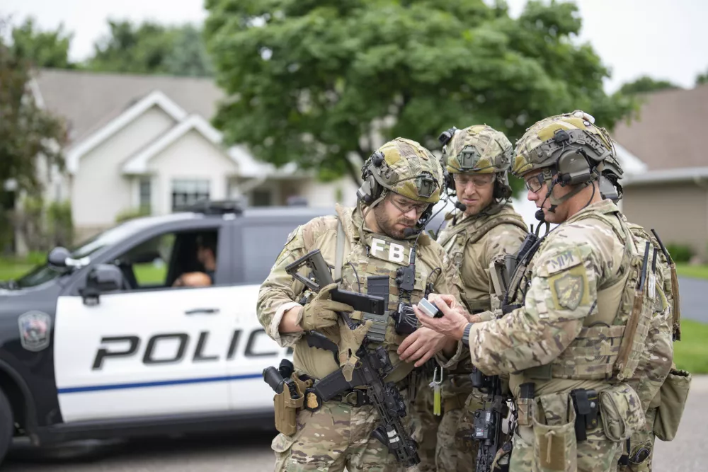 Armed FBI agents have a meeting to strategize as they search for an active shooter by sweeping a neighborhood adjacent to the home of Minnesota DFL State Representative Melissa Hortman, in Brooklyn Park, Minn. on Saturday, June 14, 2025. (Alex Kormann/Star Tribune via AP)