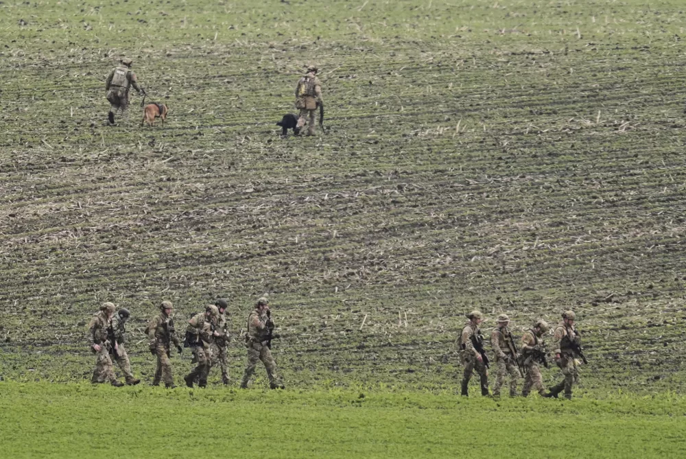 Members of law enforcement agencies walk through a field near a vehicle suspected to belong to shooting suspect, Vance Boelter, Sunday, June 15, 2025, in Belle Plaine, Minn. (AP Photo/George Walker IV)