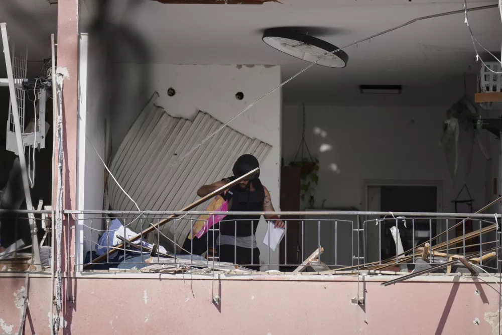 A man retrieves belongings from an apartment damaged at the site where an Iranian missile struck in Haifa, Israel, Monday, June 16, 2025. (AP Photo/Ariel Schalit)