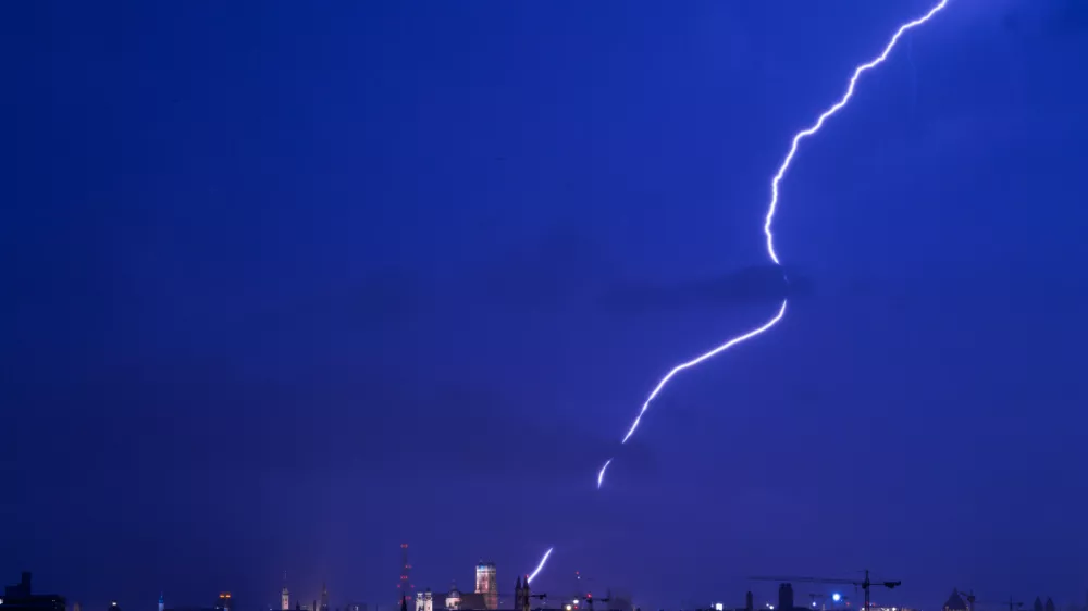 FILED - 01 August 2017, Bavaria, Munich: A strike of lightning appears over the Munich skyline in the state of Bavaria. Three climbers died after being struck by lightning while hiking in Austria's Tyrol region at the weekend. Photo: picture alliance / Peter Kneffel/dpa