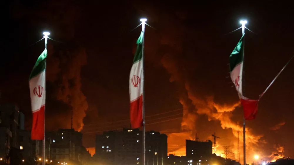 FILE PHOTO: Iranian flags fly as fire and smoke from an Israeli attack on Sharan Oil depot rise, following Israeli strikes on Iran, in Tehran, Iran, June 15, 2025. Majid Asgaripour/WANA (West Asia News Agency) via REUTERS  ATTENTION EDITORS - THIS PICTURE WAS PROVIDED BY A THIRD PARTY/File Photo / Foto: Majid Asgaripour