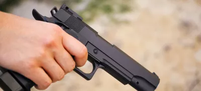 Realistic black airsoft gun in person hand. Close-up