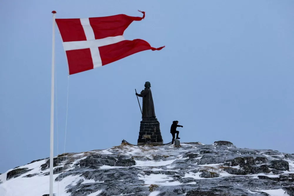 FILE PHOTO: A man walks as Danish flag flutters next to Hans Egede Statue ahead of a March 11 general election in Nuuk, Greenland, March 9, 2025. REUTERS/Marko Djurica/File Photo
