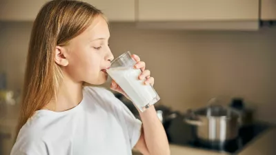 Side view of a blonde Caucasian teen taking a sip of milk from the glass / Foto: Yacobchuk