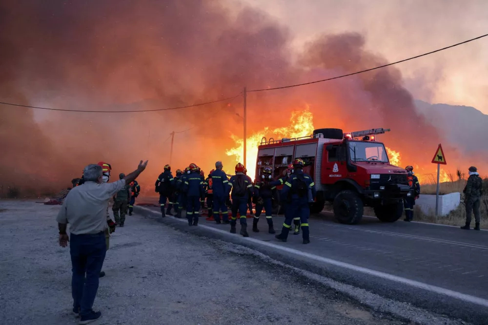 Firemen work to extinguish a wildfire, fanned by strong winds, which led to evacuation messages for villages, near the village of Karyes on Chios island, Greece, June 22, 2025. REUTERS/Konstantinos Anagnostou   TPX IMAGES OF THE DAY