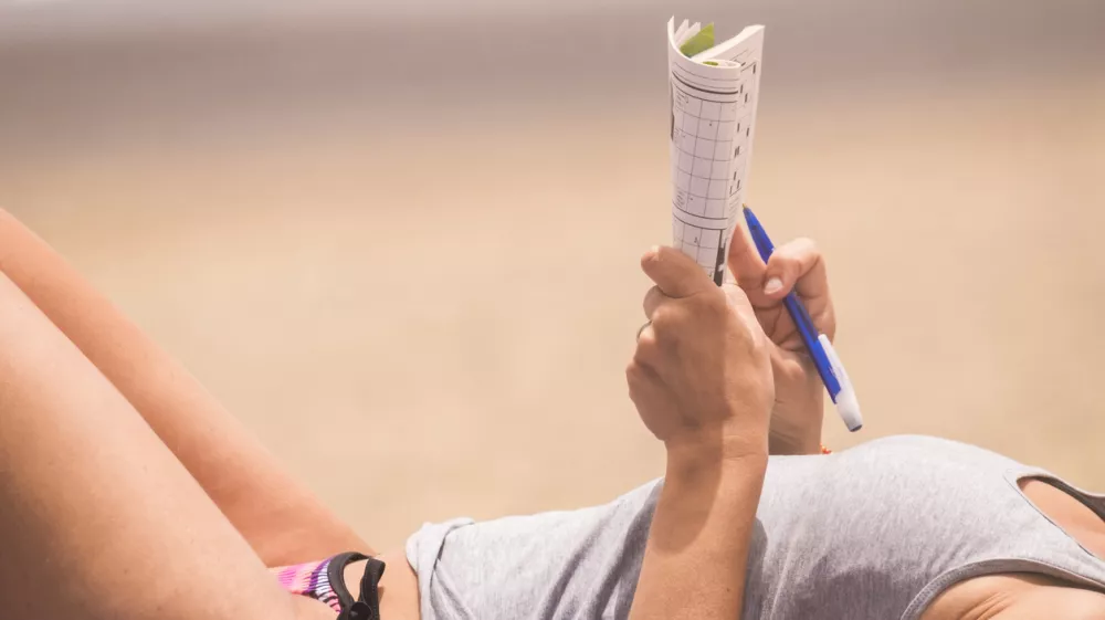 beautiful woman close up on body relaxed and have nice time doing a words play on paper. beach vacation leisure activity under the sunlight. skin tanner concept in holiday outdoor activity for lady / Foto: Simonapilolla