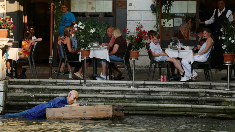 People look at an installation of a mannequin depicting Amazon Founder Jeff Bezos on a "raft" made of Amazon boxes floating in water, as part of a parody stunt by art collective Konn Artiss, ahead of the anticipated wedding of Bezos and journalist Lauren Sanchez in Venice, Italy, June 25, 2025. Click News/Handout via REUTERS  THIS IMAGE HAS BEEN SUPPLIED BY A THIRD PARTY. NO RESALES. NO ARCHIVES. MANDATORY CREDIT.