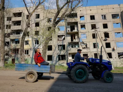 Men ride a mini tractor past a multi-storey residential building destroyed in the course of Russia-Ukraine conflict in Toshkivka (Toshkovka) in the Luhansk region, a Russian-controlled area of Ukraine, April 17, 2025. REUTERS/Alexander Ermochenko