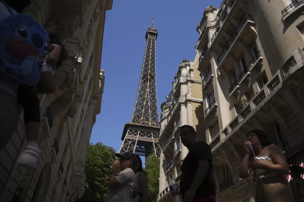 Tourists walk past the Eiffel Tower during a heat wave, Tuesday, July 1, 2025 in Paris. (AP Photo/Christophe Ena)
