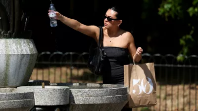 A woman fills her water bottle at a fountain in Green Park as an amber heat warning was issued in London, Britain, June 30, 2025.  REUTERS/Kevin Coombs