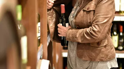 shoplifting - a woman steals a bottle of wine in a supermarket / Foto: Industryview