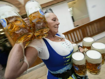 A waitress carryies beer mugs in the Hofbraeuhaus beer tent, on day one of the 189th 'Oktoberfest' beer festival in Munich, Germany, Saturday, Sept. 21, 2024. (AP Photo/Matthias Schrader)