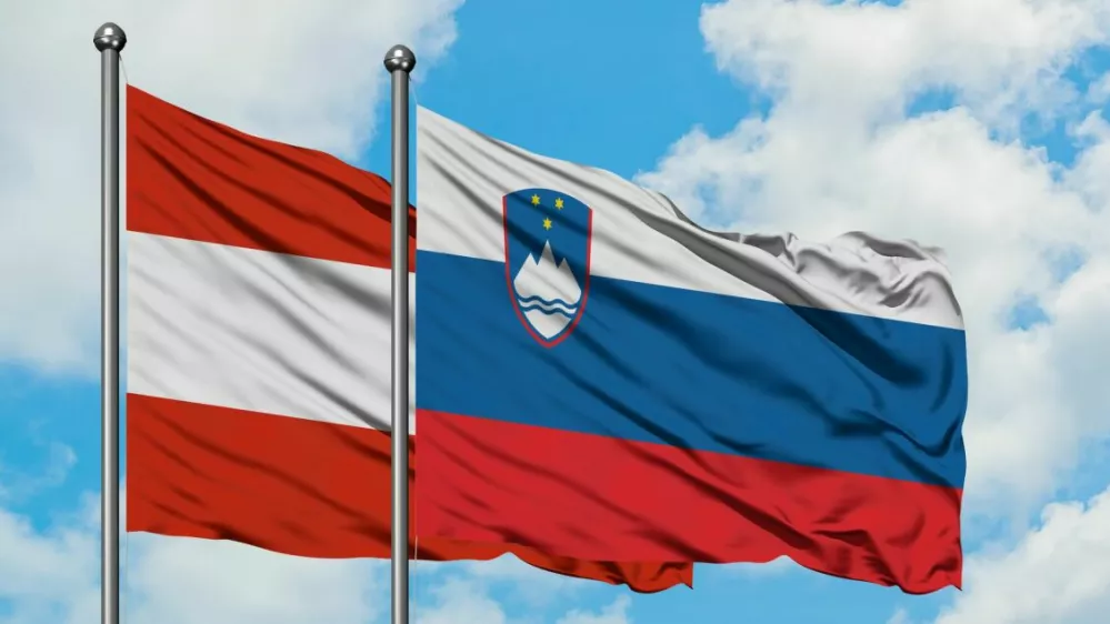 Austria and Slovenia flag waving in the wind against white cloudy blue sky together. Diplomacy concept, international relations.