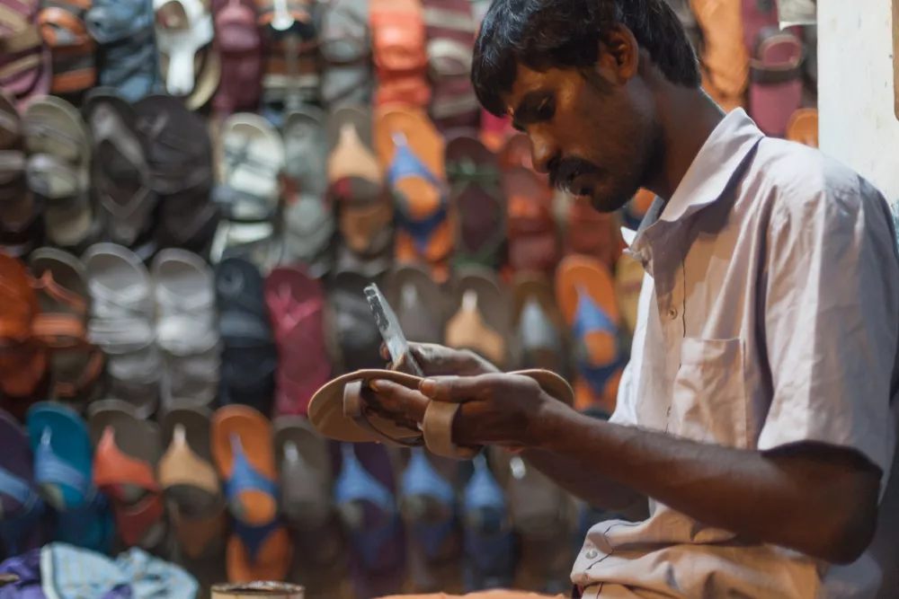 Kovalam, India - November 6, 2014: A shoemaker in his workshop in Kerala village. Services and hand-making is very cheap in India.