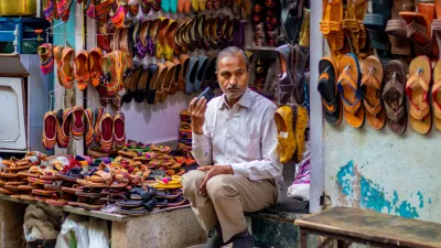 nathdwara, India &ndash; February 21, 2021: A shopkeeper sitting outside at his Juttis & Mojaris shop listening to something on the phone
