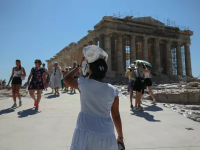 A woman protects her head from the sun, while visiting the Acropolis, at the start of a 3-days heatwave with temperatures expected to overpass 40 Celsius degrees, in Athens, Greece, July 7, 2025. REUTERS/Louisa Gouliamaki