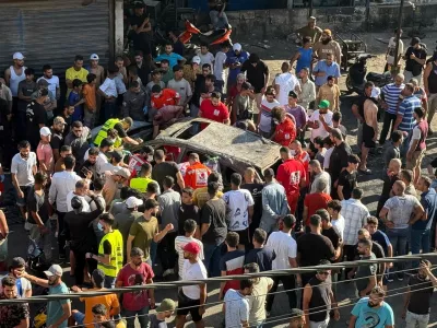 People gather near a damaged car after the Israeli military said in a statement it struck a "key" figure from Palestinian militant group Hamas, in Ayrounieh, northern Lebanon July 8, 2025. REUTERS/Walid Saleh
