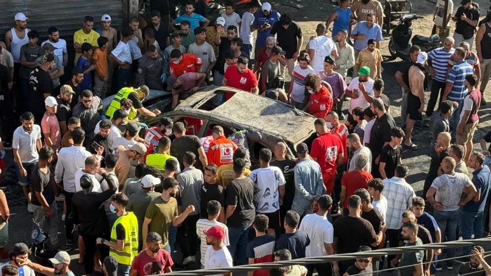 People gather near a damaged car after the Israeli military said in a statement it struck a "key" figure from Palestinian militant group Hamas, in Ayrounieh, northern Lebanon July 8, 2025. REUTERS/Walid Saleh