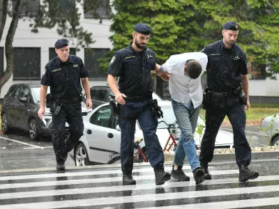 Emanuel Rep v spremstvu policistov na zasli&scaron;anje v Varaždinu. Sumijo ga umora mame s sekiro ter poskusa umorov polbrata in očima. 