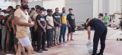 A Greek coast guard gives water to migrants from Africa as they take a shelter in Agia port, Chania, Crete island, Greece, Monday, July 7, 2025. (AP Photo/Giannis Angelakis)