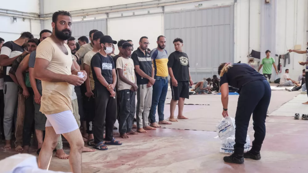 A Greek coast guard gives water to migrants from Africa as they take a shelter in Agia port, Chania, Crete island, Greece, Monday, July 7, 2025. (AP Photo/Giannis Angelakis)