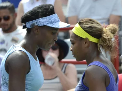 Venus Williams, left, and her sister Serena walk to their seats between games during semifinal play at the Rogers Cup tennis tournament, Saturday, Aug. 9, 2014 in Montreal. (AP Photo/The Canadian Press, Paul Chiasson)