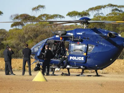Police wait by a helicopter in Beacon, Western Australia, Friday, July 11, 2025, as they prepare to search for missing German backpacker Carolina Wilga. (ABC News via AP)