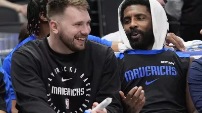 Sitting on the bench Dallas Mavericks guard Luka Doncic, left, shares a laugh with teammate fellow guard Kyrie Irving during a preseason NBA basketball game against the Milwaukee Bucks Thursday, Oct. 17, 2024, in Dallas. (AP Photo/LM Otero)