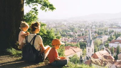 Family on background of Ljubljana, Slovenia, Europe. Woman with two little children looks at panorama of european city from the hill. Mother and kids outdoors at spring or summer time. / Foto: Nataliaderiabina