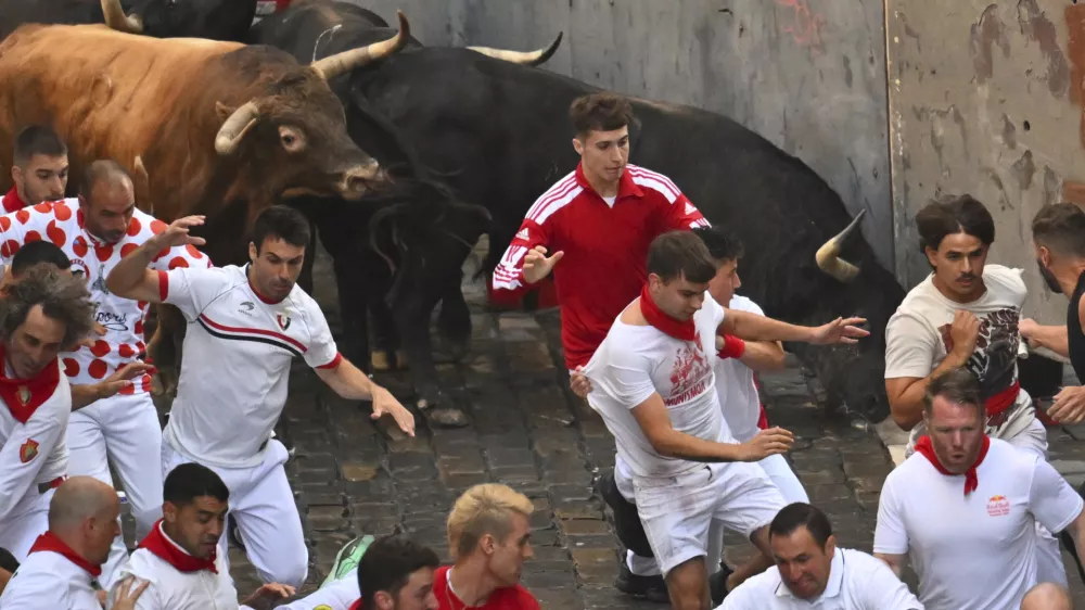 Revelers run alongside La Palmosilla's fighting bulls during the seventh running of the bulls at the San Ferm&iacute;n festival in Pamplona, Spain, Sunday, July 13, 2025. (AP Photo/Miguel Oses)