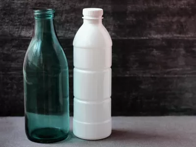 Glass milk bottle and plastic white bottle on grey background. Reusable packaging. The concept of environmental protection.Empty space for text. Selective focus.