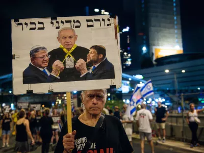 A protestor hold up a sign with Bezalel Smotrich and Itamar Ben Gvir strangle PM Benjamin Netanyahu with a yellow ribbon that reads: ?Senior political figure?. Thousands of Israelis demonstrated with the hostage?s families against Prime Minister Benjamin Netanyahu, demanding an immediate hostage deal and ceasefire - as Israel awaits for the Iranian and Hezbollah attack. Tel Aviv, Israel. August 10th 2024. (Matan Golan / Sipa USA).