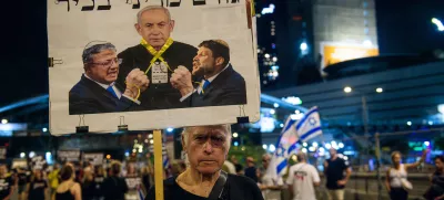 A protestor hold up a sign with Bezalel Smotrich and Itamar Ben Gvir strangle PM Benjamin Netanyahu with a yellow ribbon that reads: ?Senior political figure?. Thousands of Israelis demonstrated with the hostage?s families against Prime Minister Benjamin Netanyahu, demanding an immediate hostage deal and ceasefire - as Israel awaits for the Iranian and Hezbollah attack. Tel Aviv, Israel. August 10th 2024. (Matan Golan / Sipa USA).