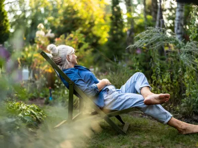 Mature woman relaxing in deckchair in her garden / Foto: Piksel