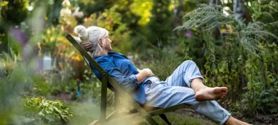 Mature woman relaxing in deckchair in her garden / Foto: Piksel